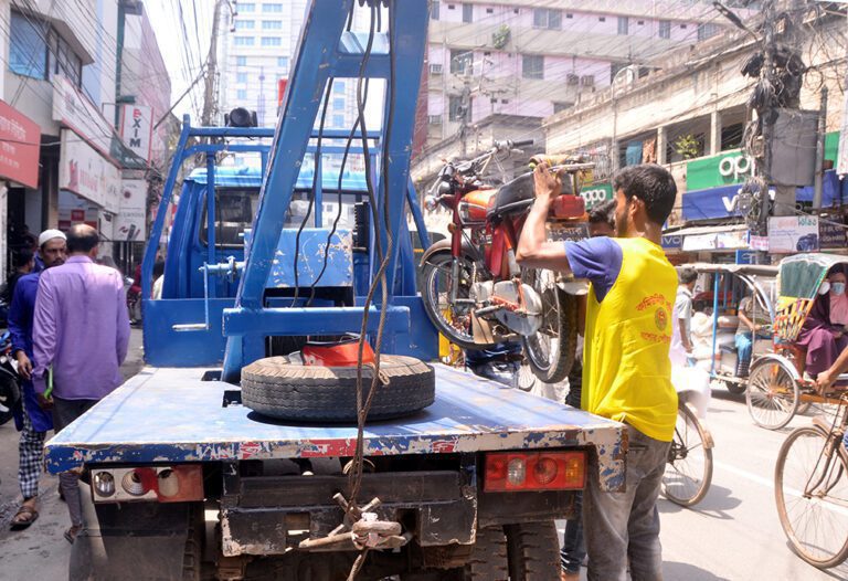 যশোর শহরের এমকে সড়কের পাশে অবৈধ মোটরসাইকেল পার্কিং করায় ট্রাফিক পুলিশ র‌্যোকারে করে উঠিয়ে নিয়ে যায়। ছবি : ইলিয়াস সাজু